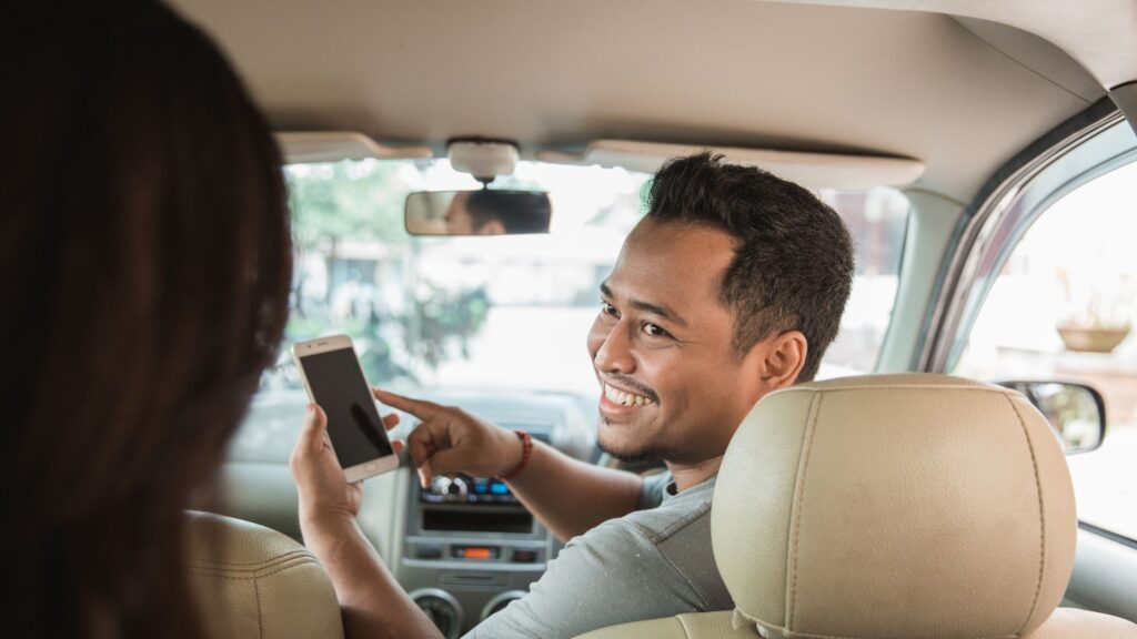 Photo of a man in a car with a phone, looks like he could be an Uber driver