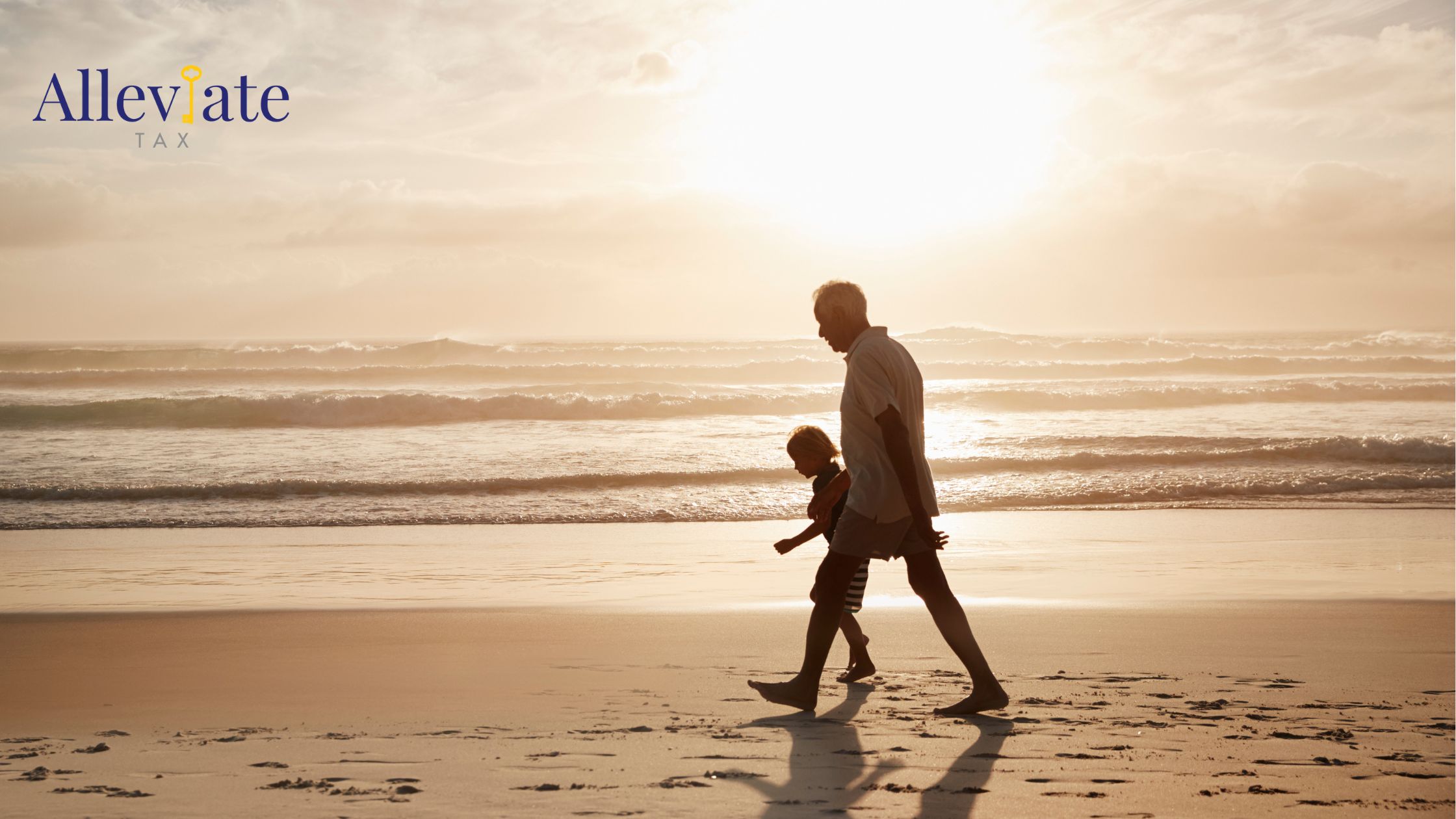 Grandparent and grandchild walk hand in hand on the beach at sunset.