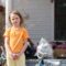 Child stands in front of a cluttered house