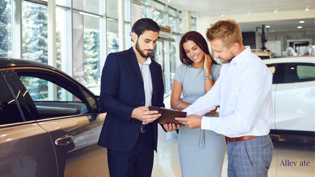 Couple signs a contract to buy a new car with a car salesperson at a dealership.