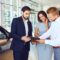 Couple signs a contract to buy a new car with a car salesperson at a dealership.